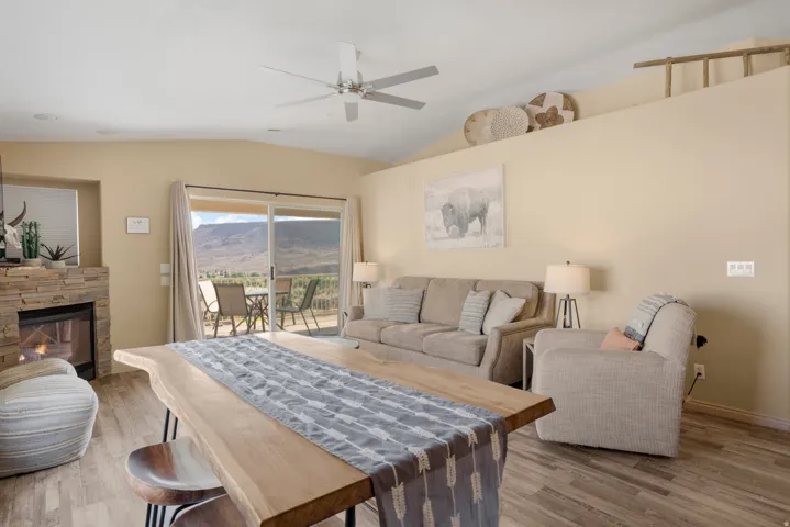 Expansive living area featuring a stone-clad fireplace and wood-finish flooring