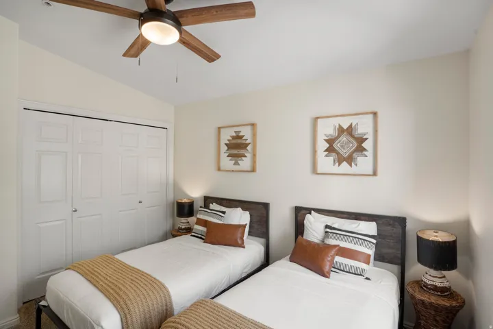 Room featuring a ceiling fan with light fixture, ample closet space with bi-fold doors, and neutral wall tones