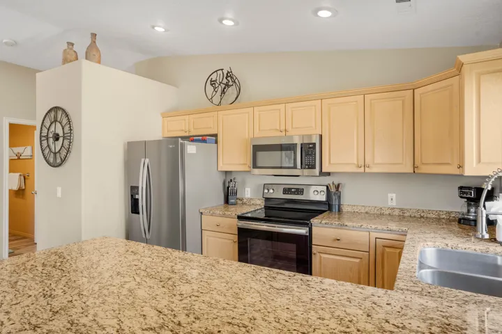 Kitchen featuring stone countertops, natural wood-finish cabinetry, a stainless steel sink with a gooseneck faucet, and recessed lighting