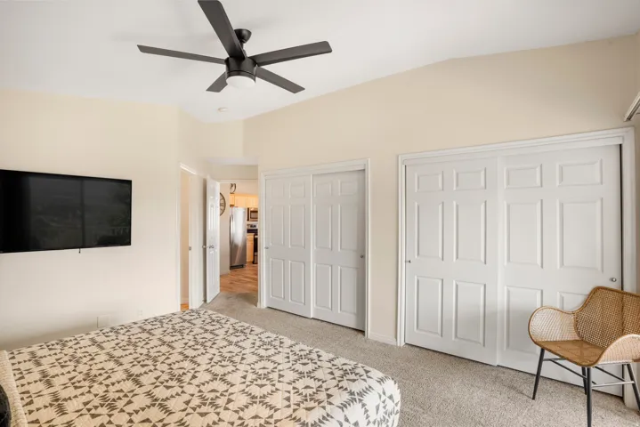 Bedroom featuring vaulted ceilings, a ceiling fan with integrated lighting, and carpet flooring