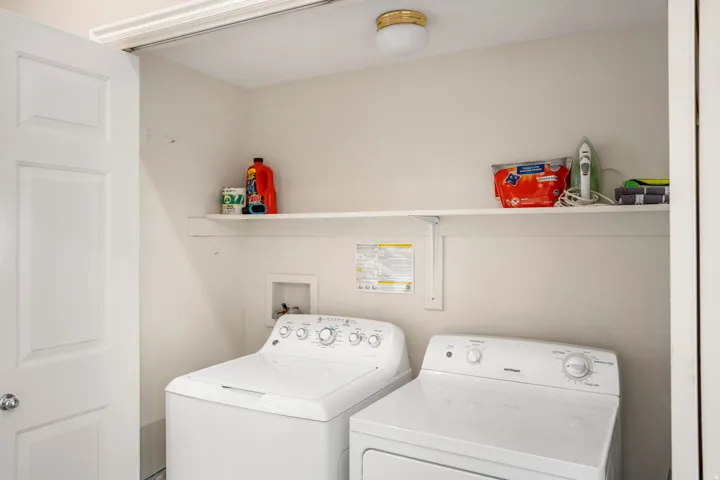 Dedicated laundry area featuring a flush-mount ceiling light, paneled door, and a built-in wall shelf for storage