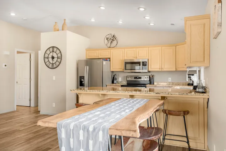 Kitchen featuring light wood-finish cabinetry, granite-style countertops, and stainless steel appliances