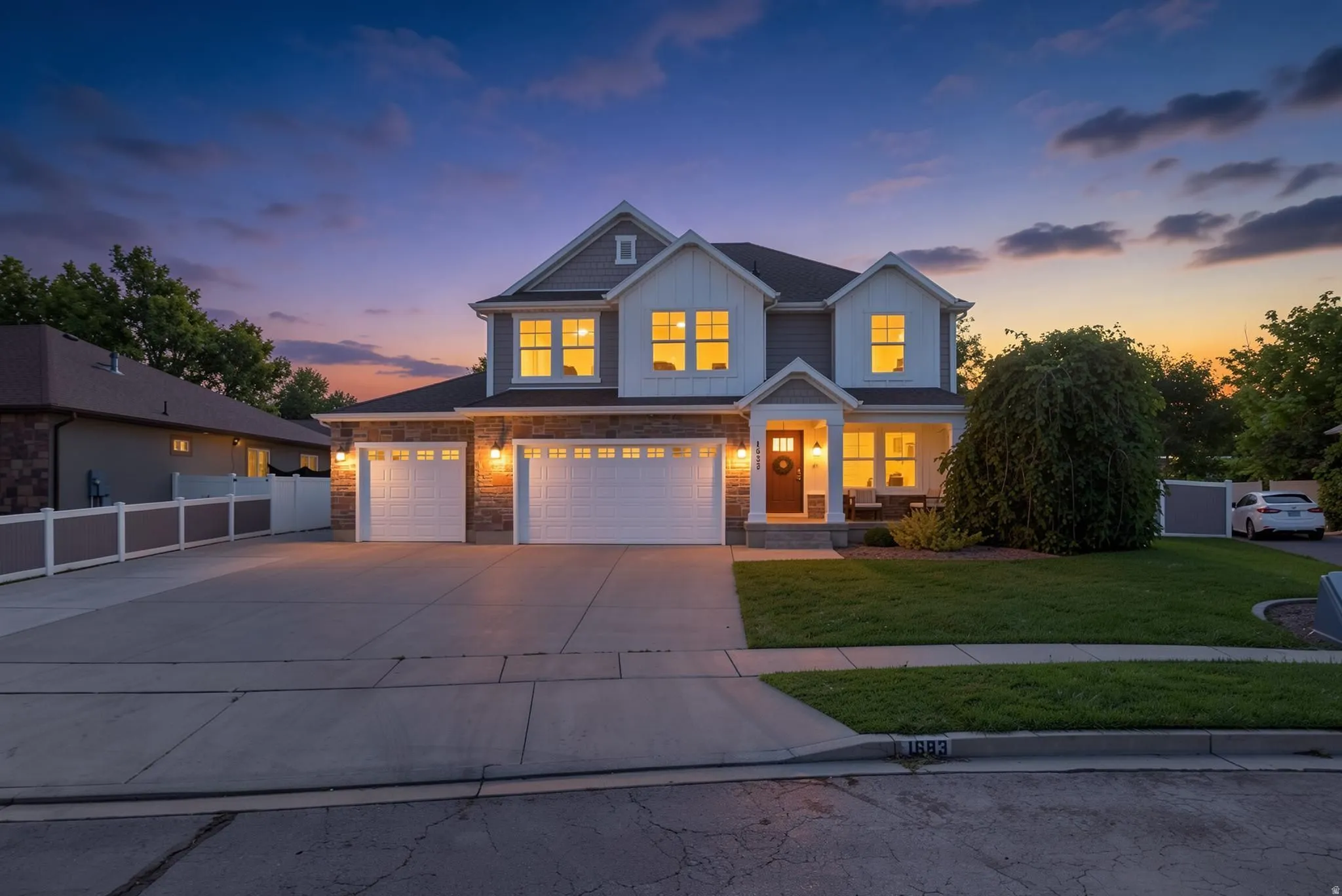 Contemporary home with a stone and siding exterior, featuring a covered front porch and a two-car garage