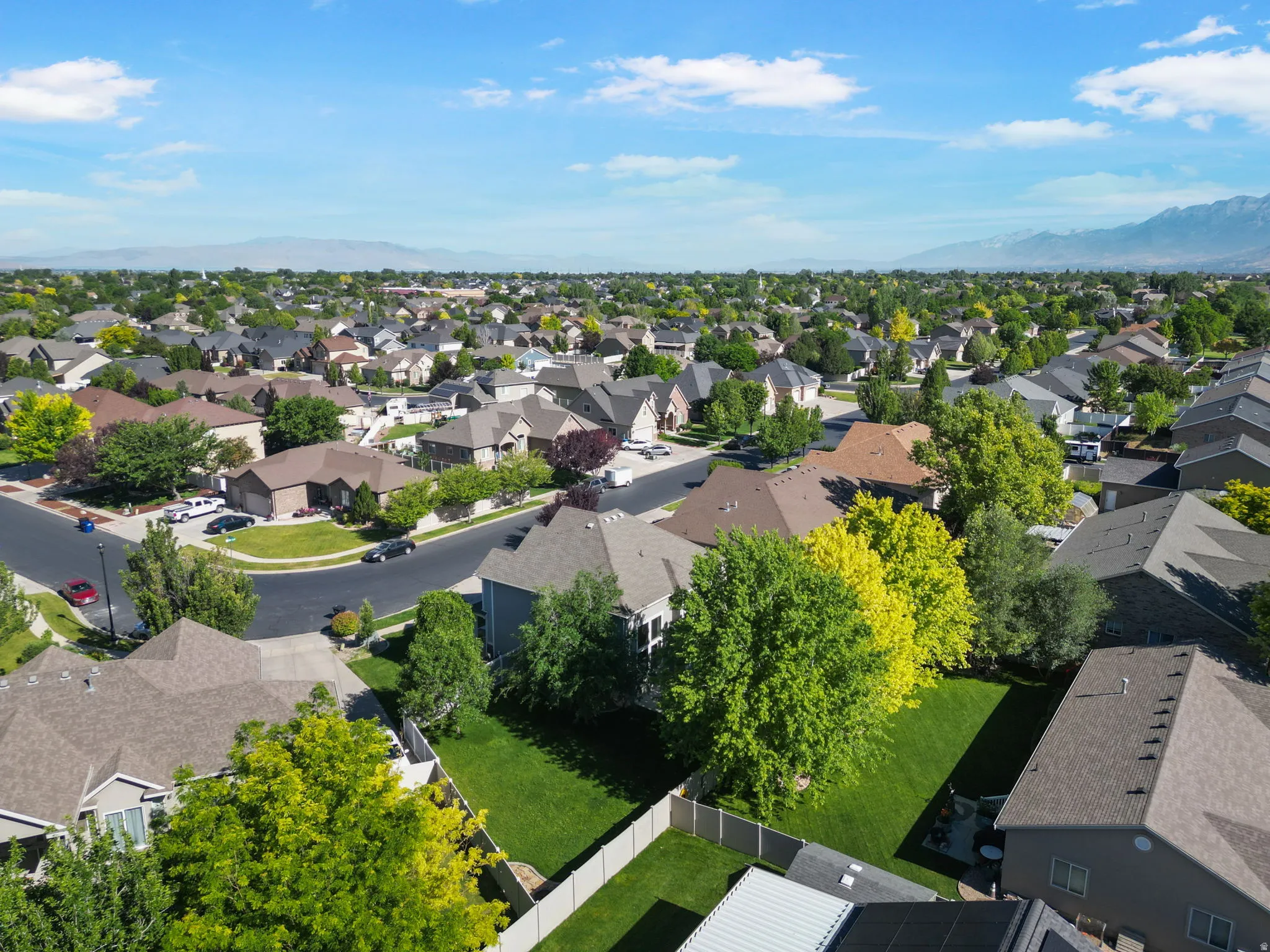 Expansive aerial view of a residential neighborhood with mature trees and mountain scenery