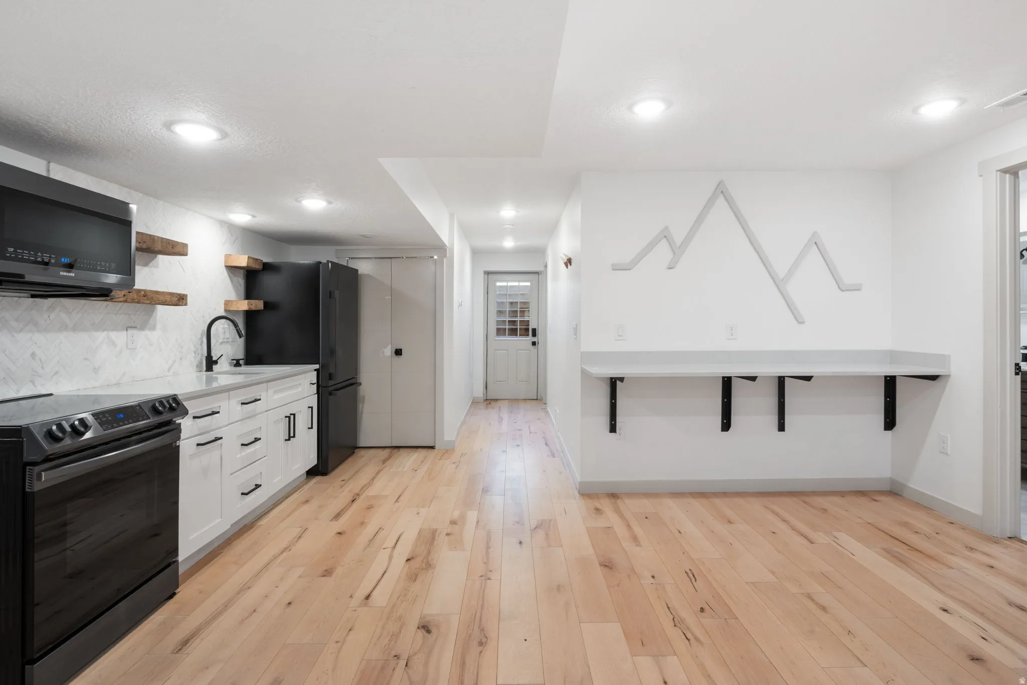 Bright open-concept space featuring wood-finish flooring, recessed lighting, and a white color palette