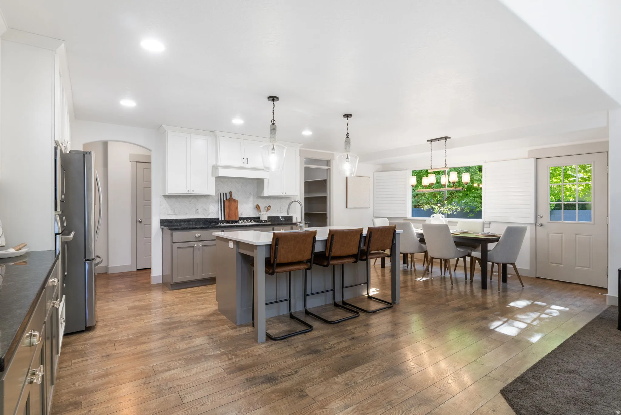 Open-concept kitchen and dining area featuring wood-finish flooring, recessed lighting, and a white and gray color palette