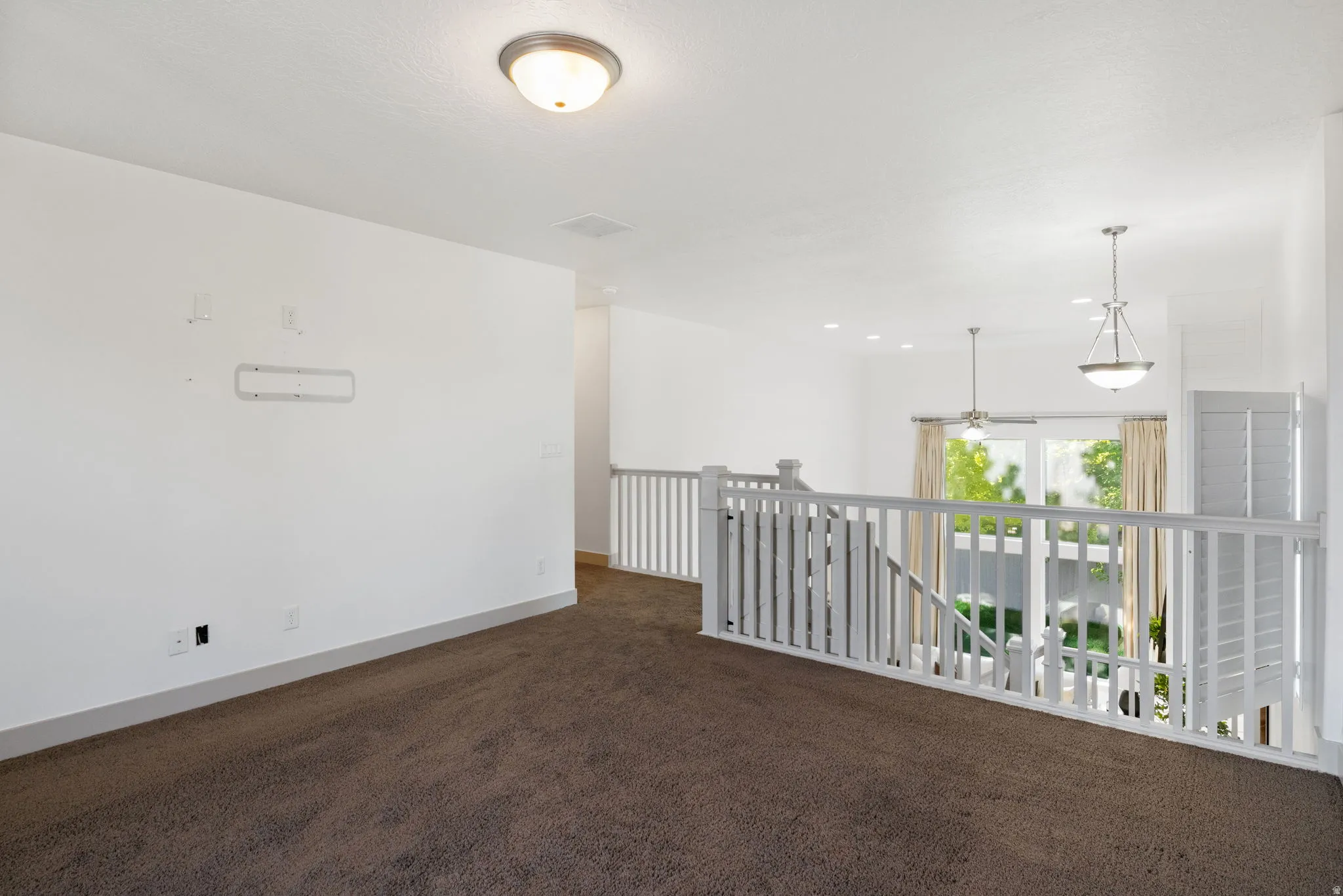 Carpeted loft area featuring white painted railings, a flush-mount ceiling light, and recessed lighting
