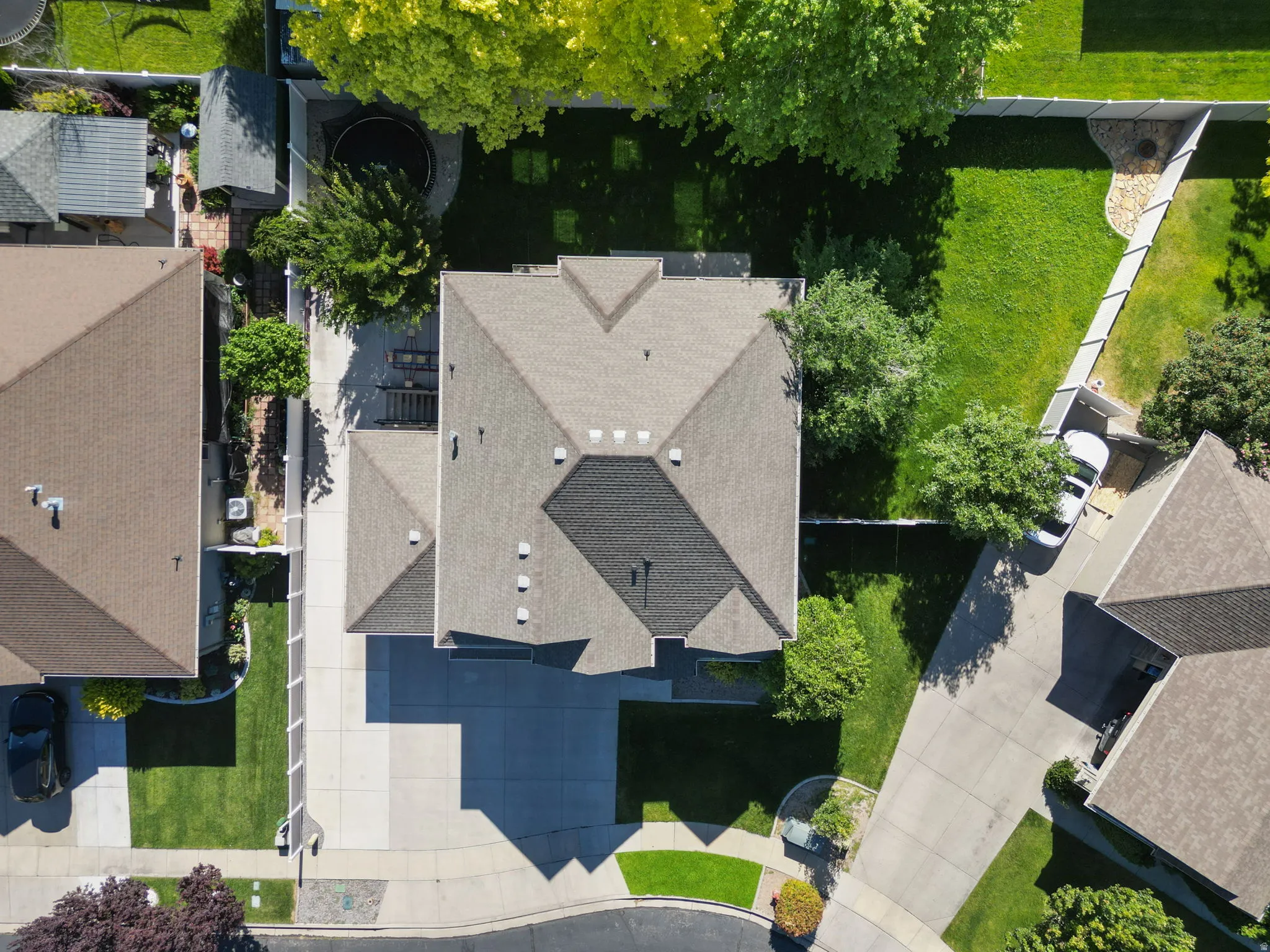Aerial view showcasing a residential property with a multi-pitched roofline and a substantial concrete driveway