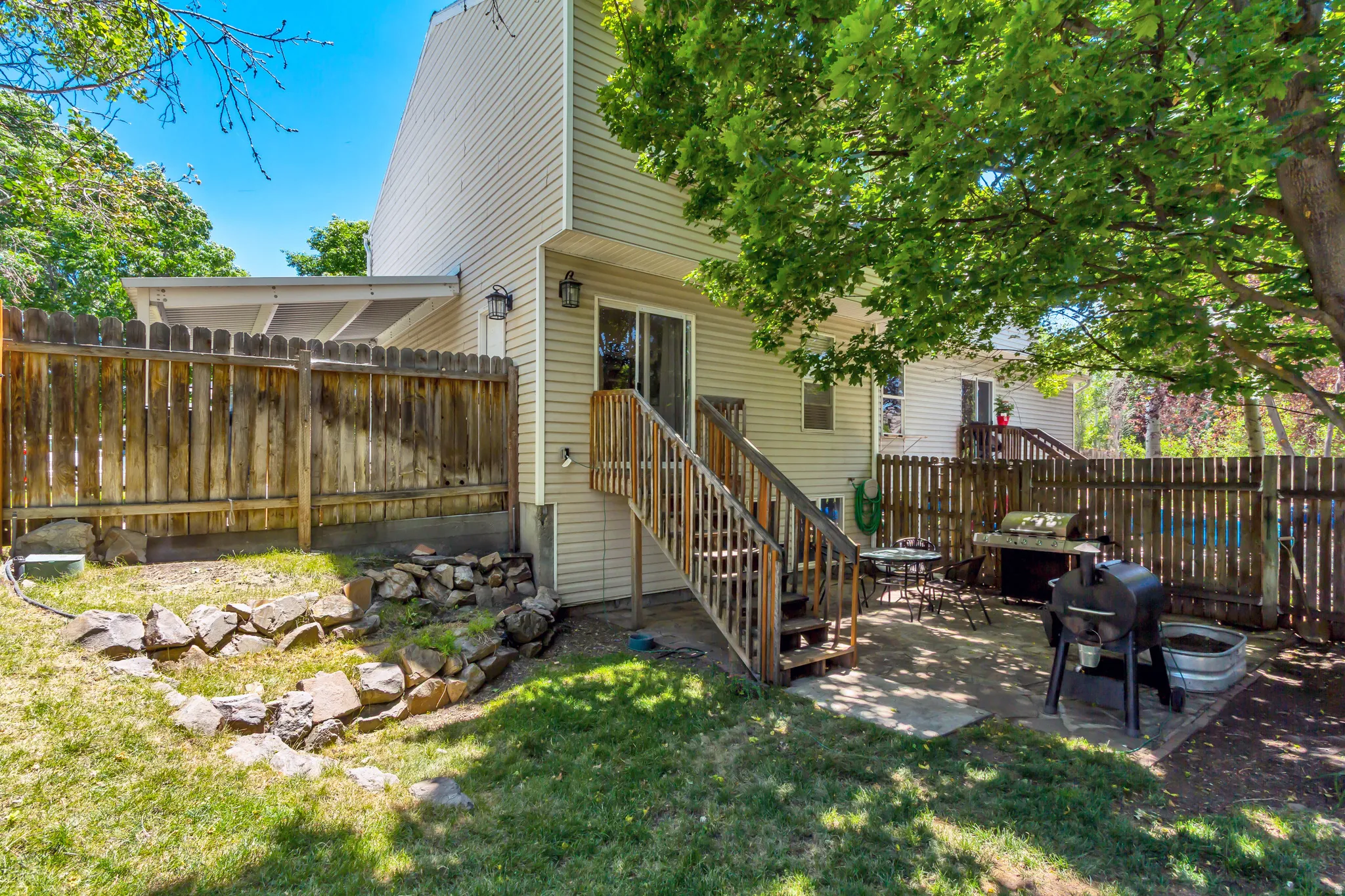 Rear exterior featuring a patio, wood privacy fencing, and a wooden deck with stairs