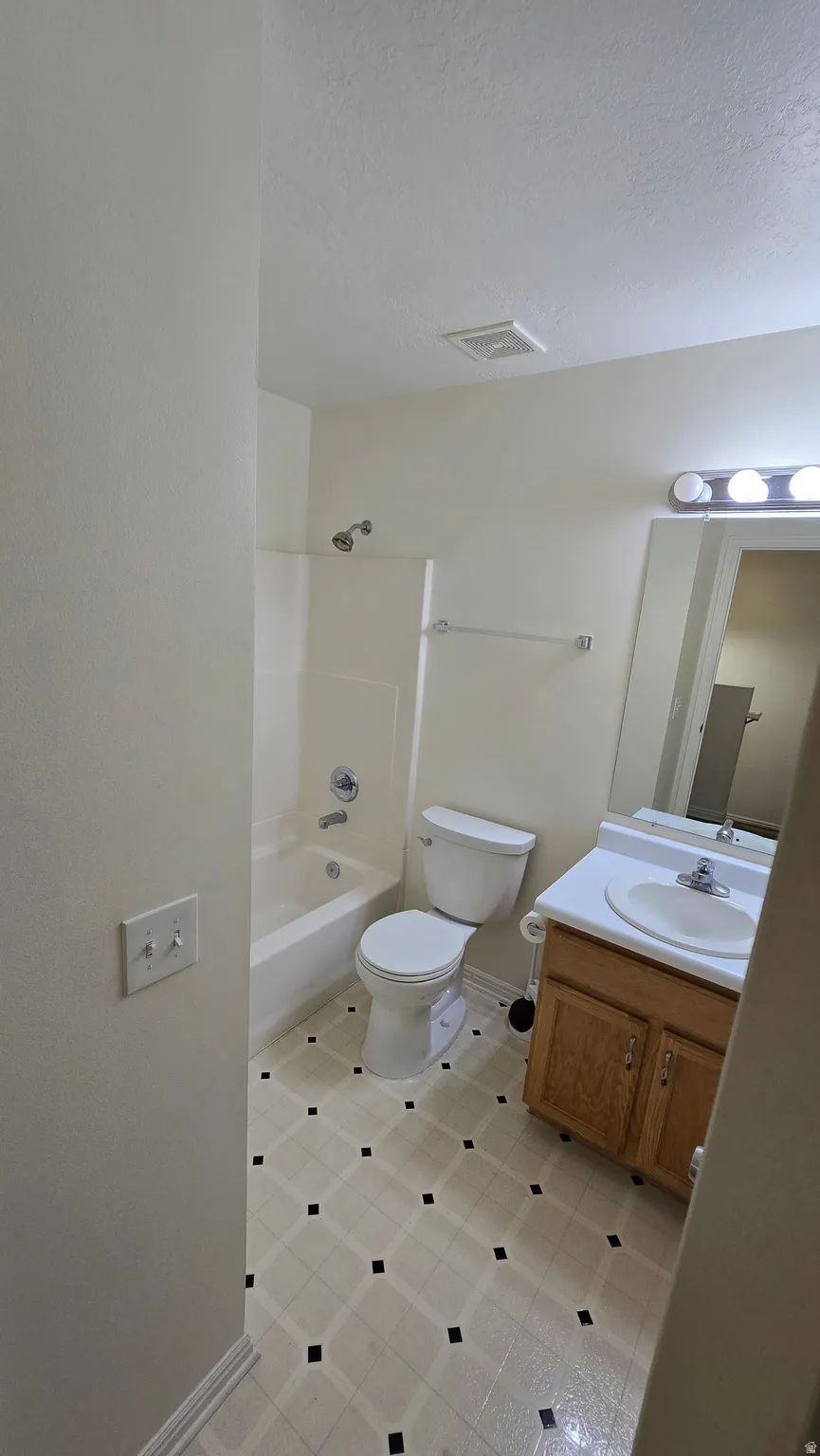Bathroom featuring a tub/shower combination, toilet, and vanity with an integrated sink
