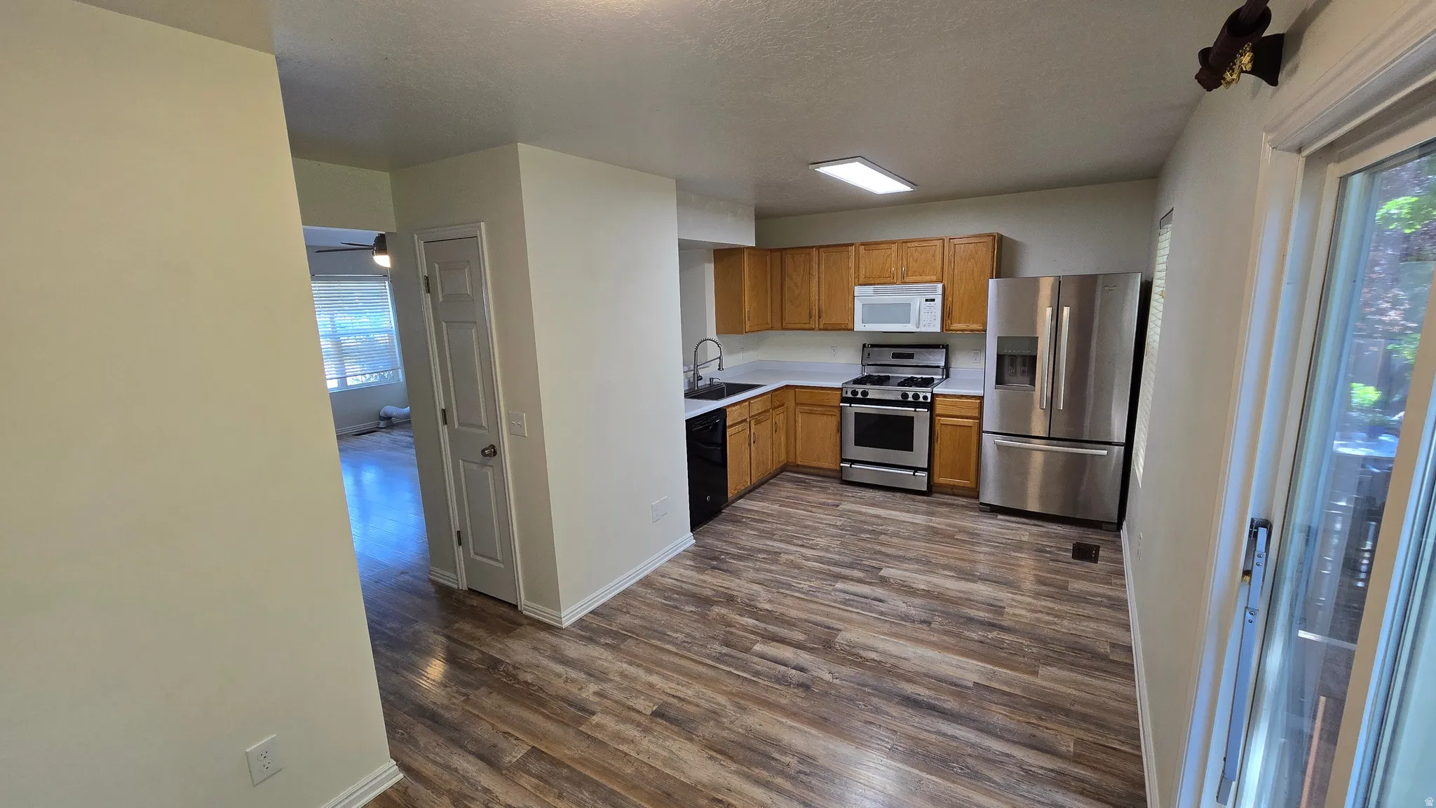Kitchen featuring wood-finish flooring, wood cabinetry, white countertops, and stainless steel appliances