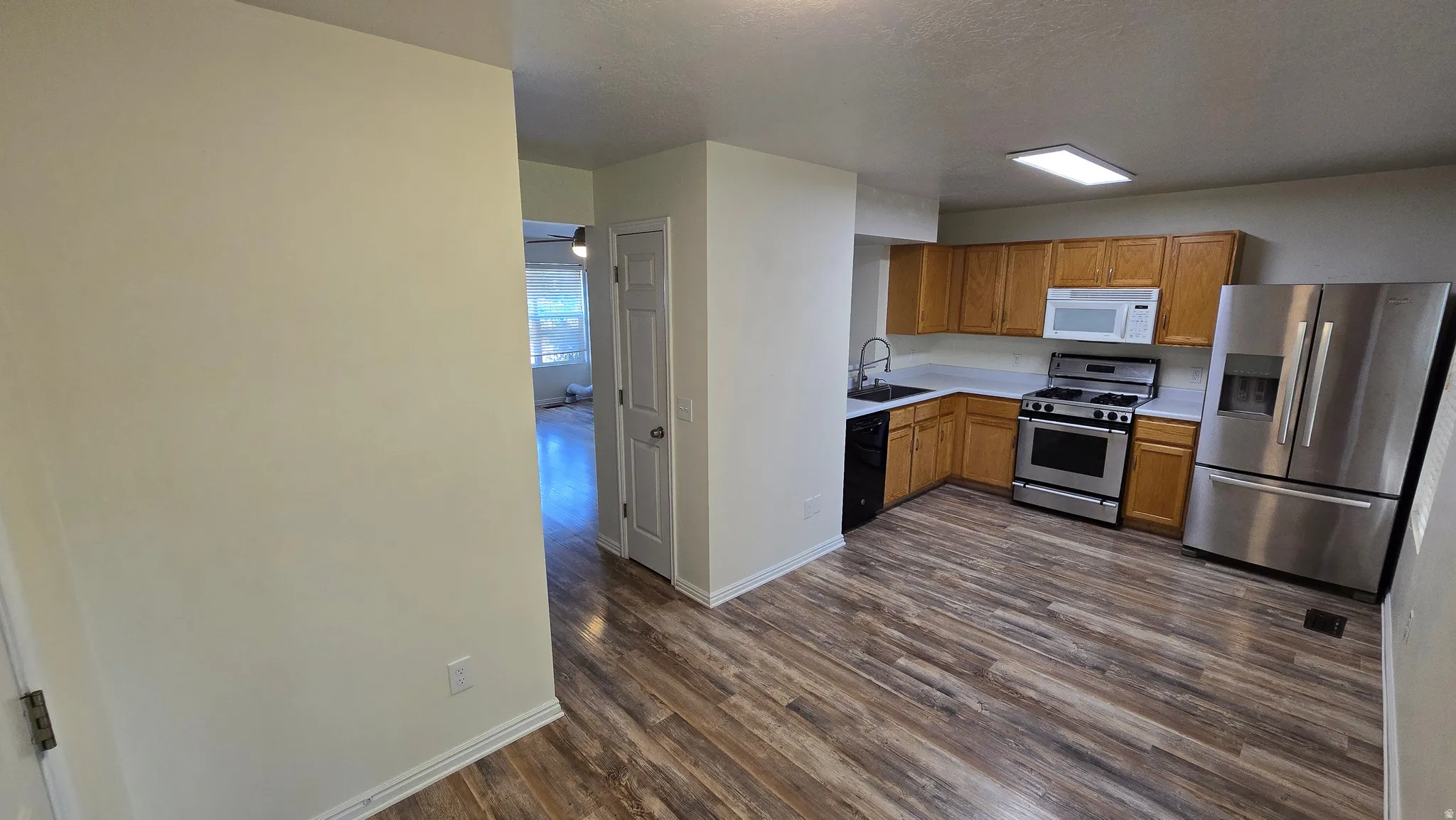 Kitchen featuring wood-finish flooring, wood cabinetry, stainless steel appliances, and a rectangular ceiling light fixture