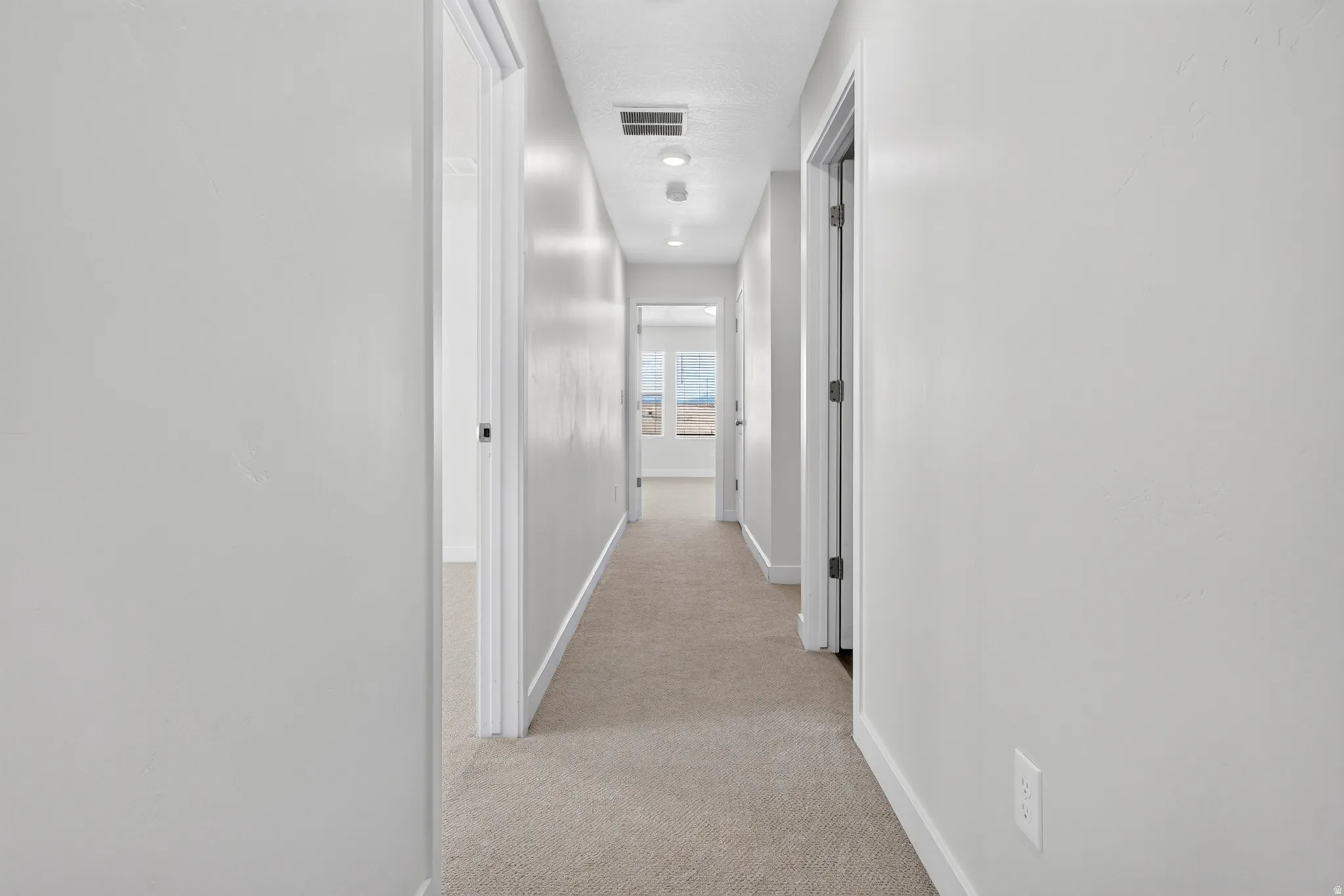 Hallway featuring neutral-toned carpeting and white painted walls