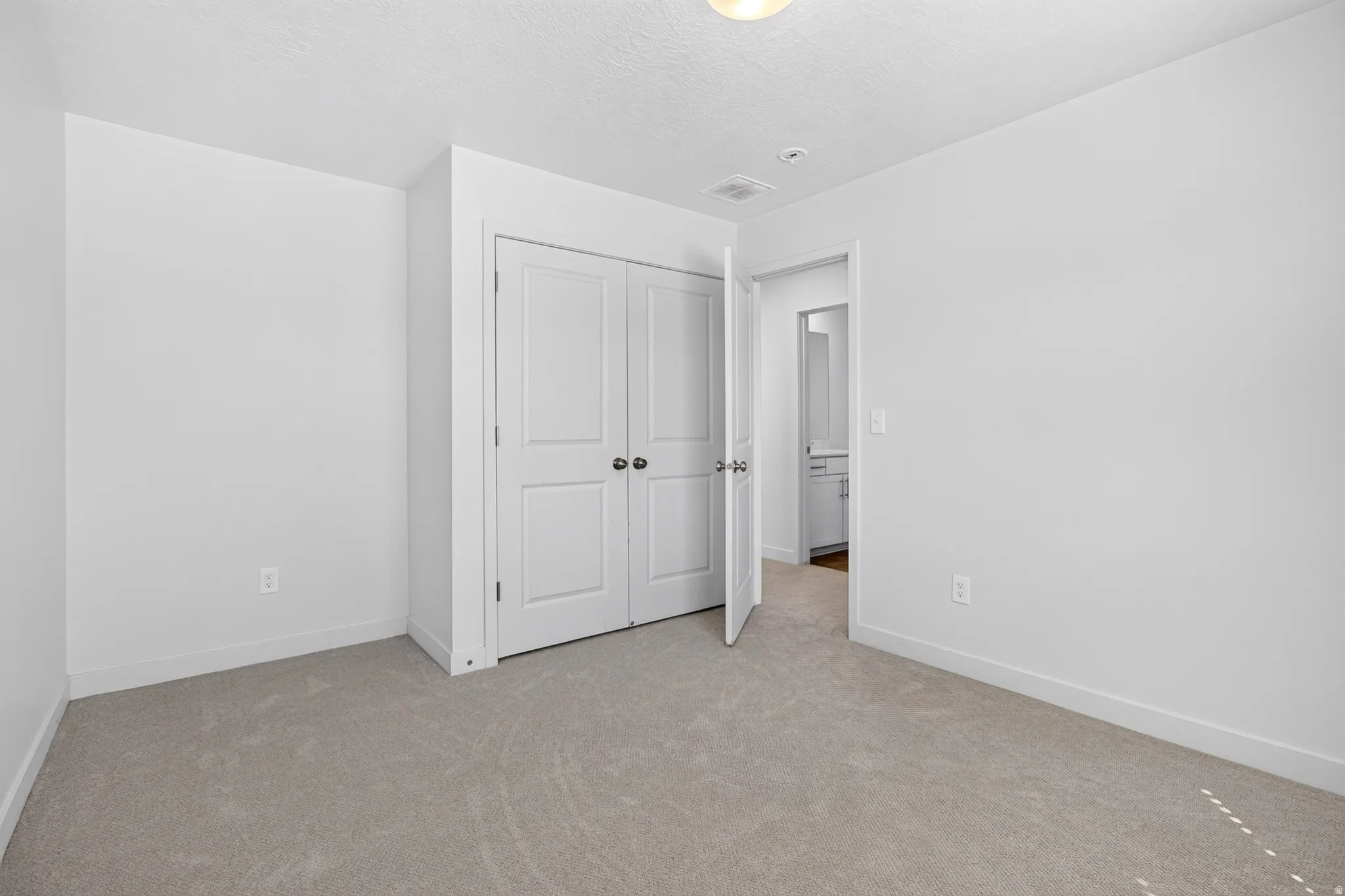 Neutral-toned carpet flooring and white baseboards define this room