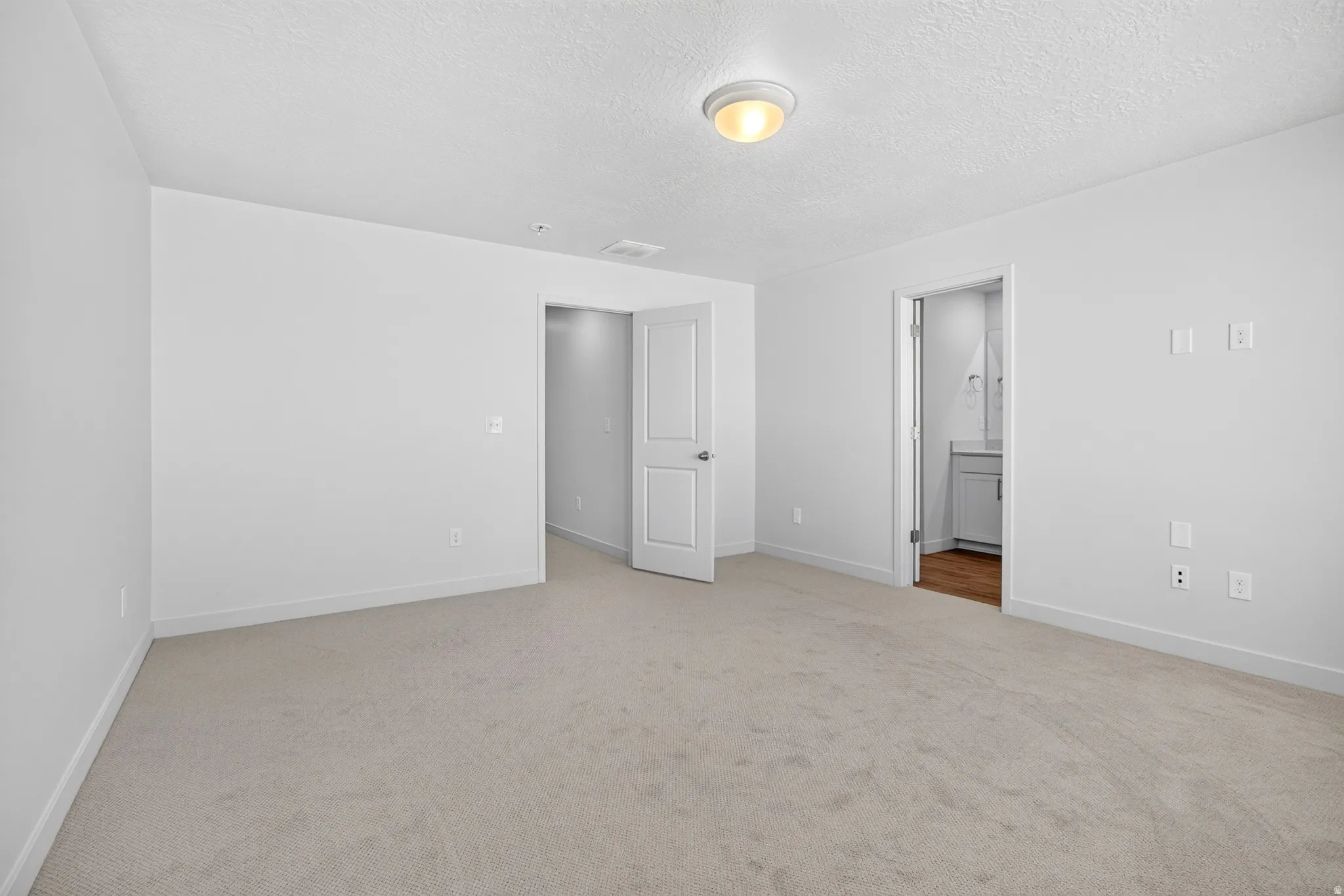Neutral-toned carpet flooring with white baseboards throughout