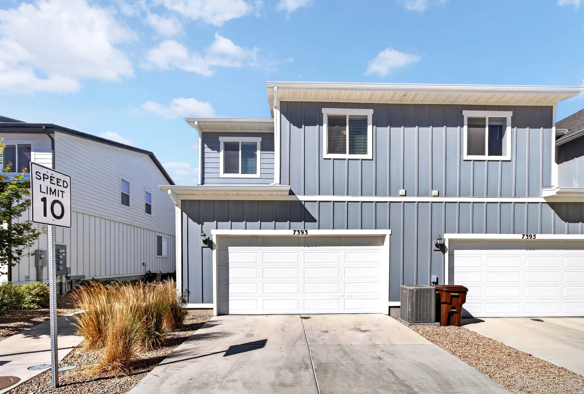Modern townhouse exterior featuring vertical board and batten siding, white-framed windows, and an integrated garage