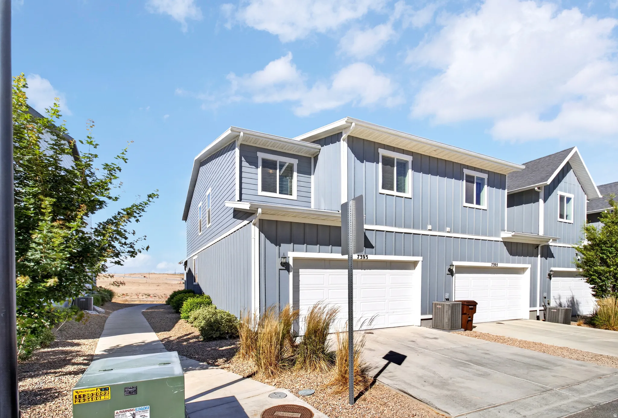 Modern townhome exterior featuring vertical siding, white-framed windows, and an attached garage