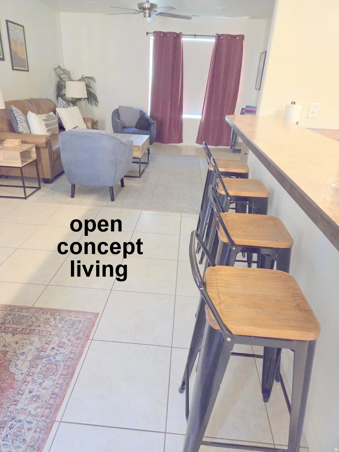 Kitchen counter seating with tiled flooring extending into an open living area