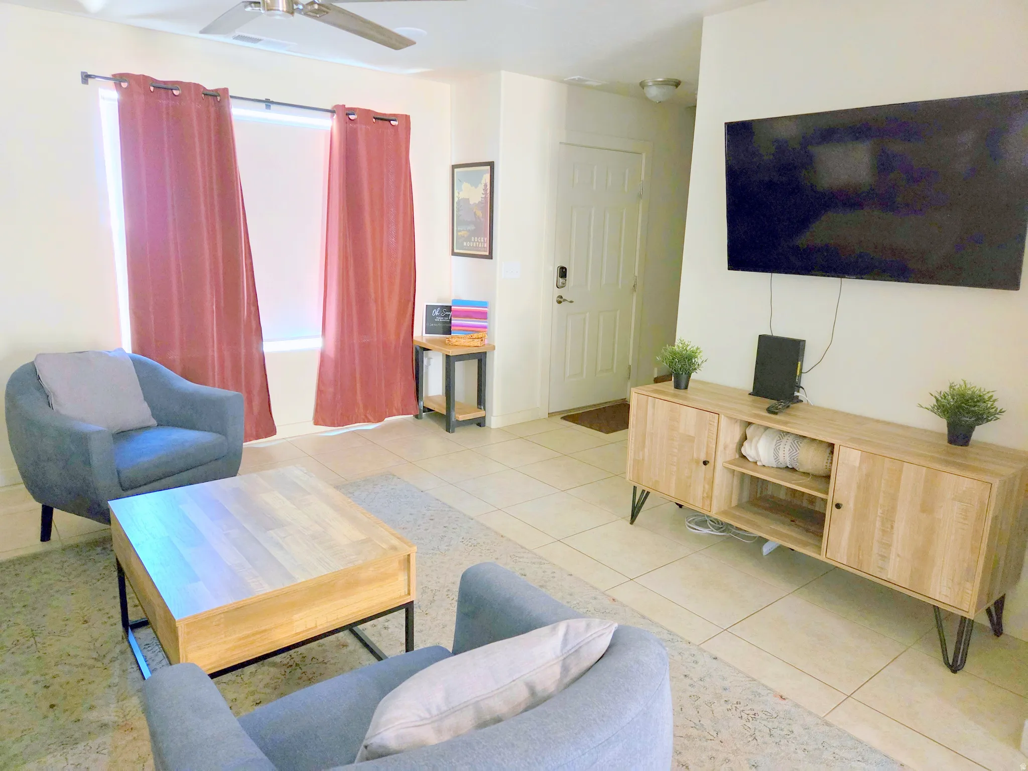 Open concept living area featuring tile flooring, a ceiling fan, and a prominent window