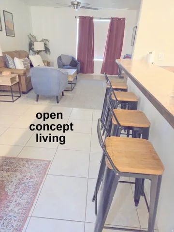 Kitchen counter seating with tiled flooring extending into an open living area