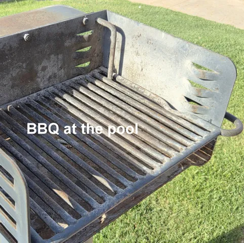 Built-in outdoor grill with a metal grate cooking surface, supported by a sturdy metal frame