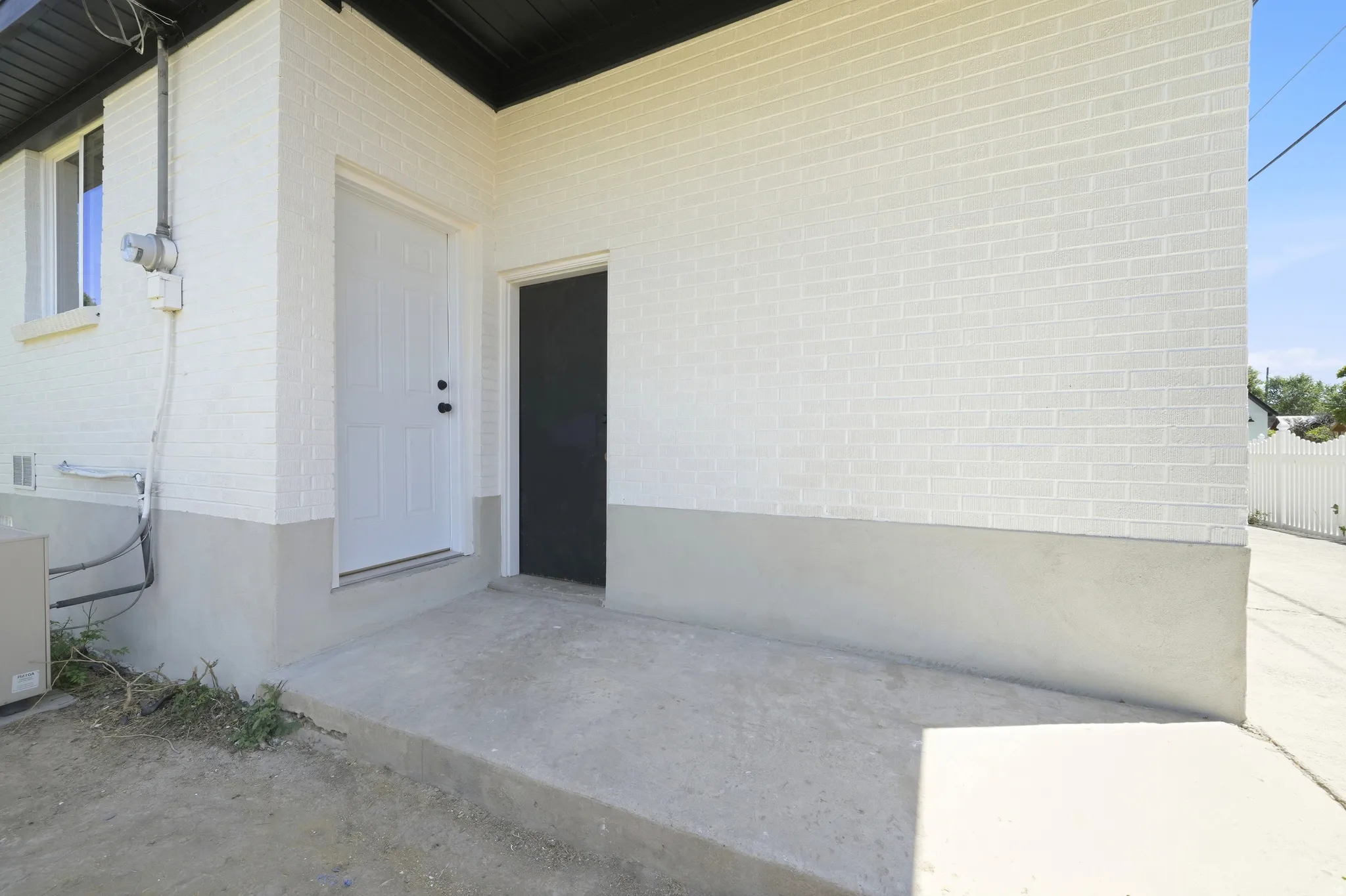 Exterior wall featuring white painted brick and a contrasting gray foundation