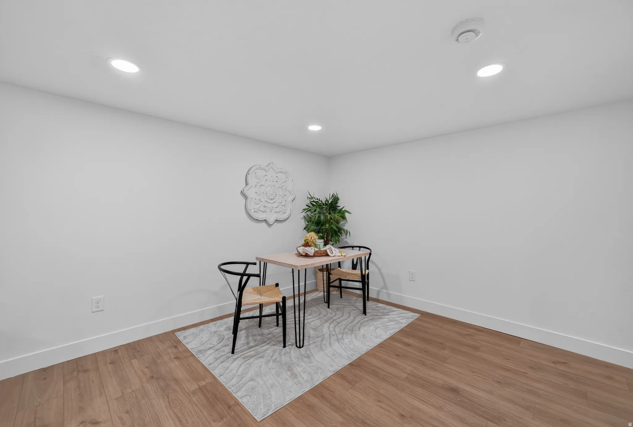 Spacious room featuring light wood-finish flooring, white baseboards, and neutral wall tones