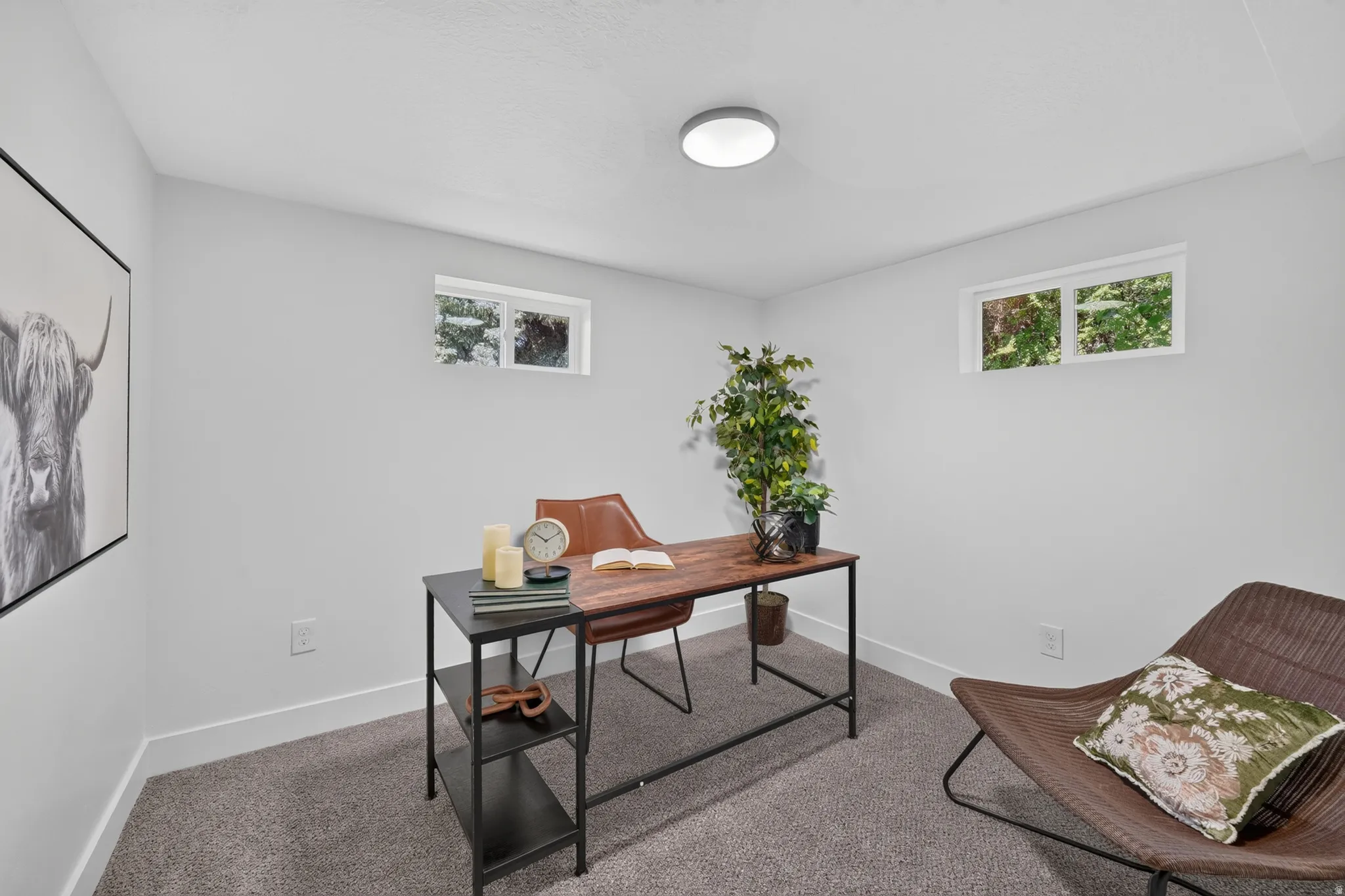 Bright room featuring two windows with exterior foliage, neutral wall tones, white trim, and gray carpet