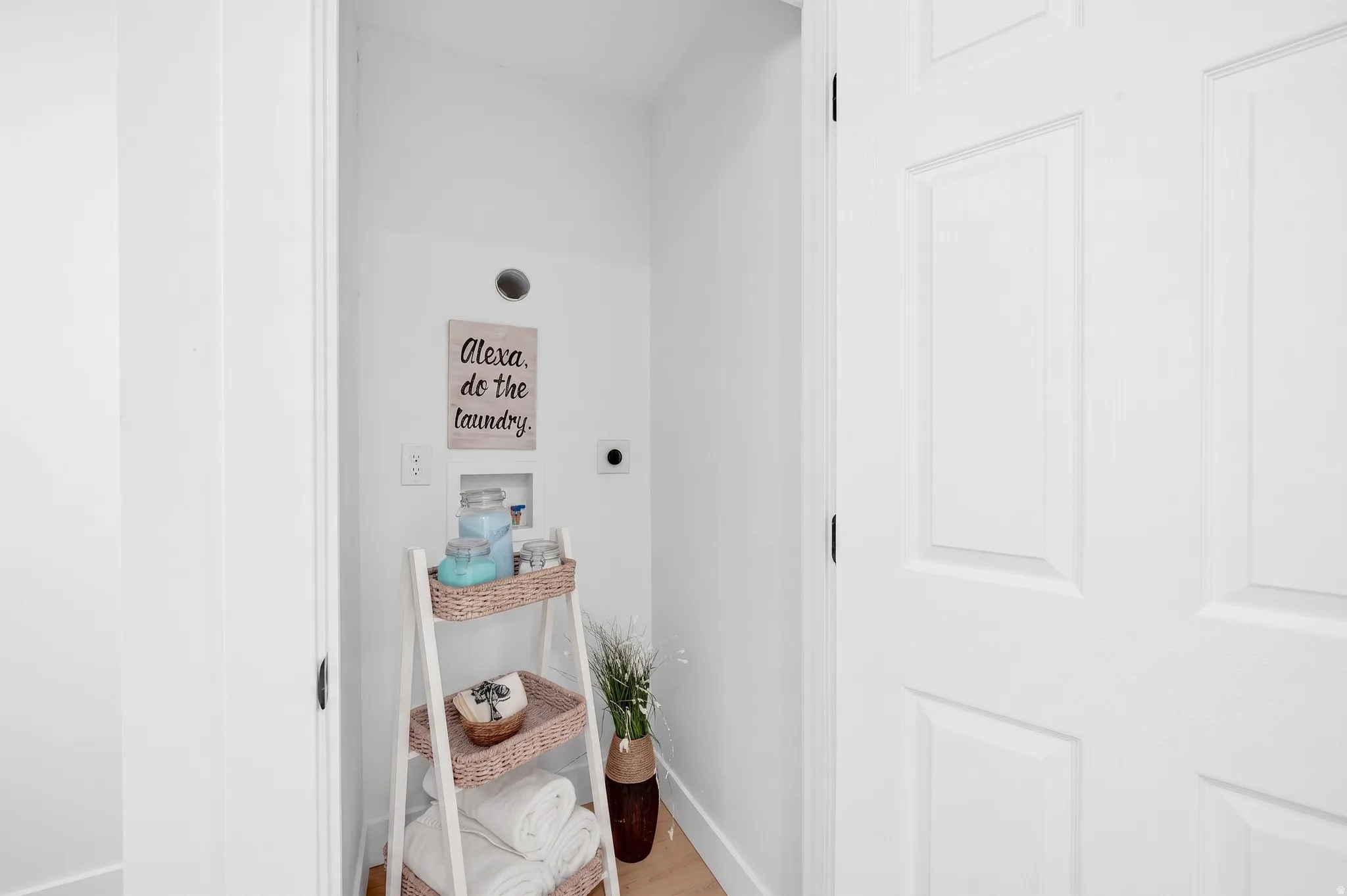 Dedicated laundry area featuring white walls and light wood-finish flooring