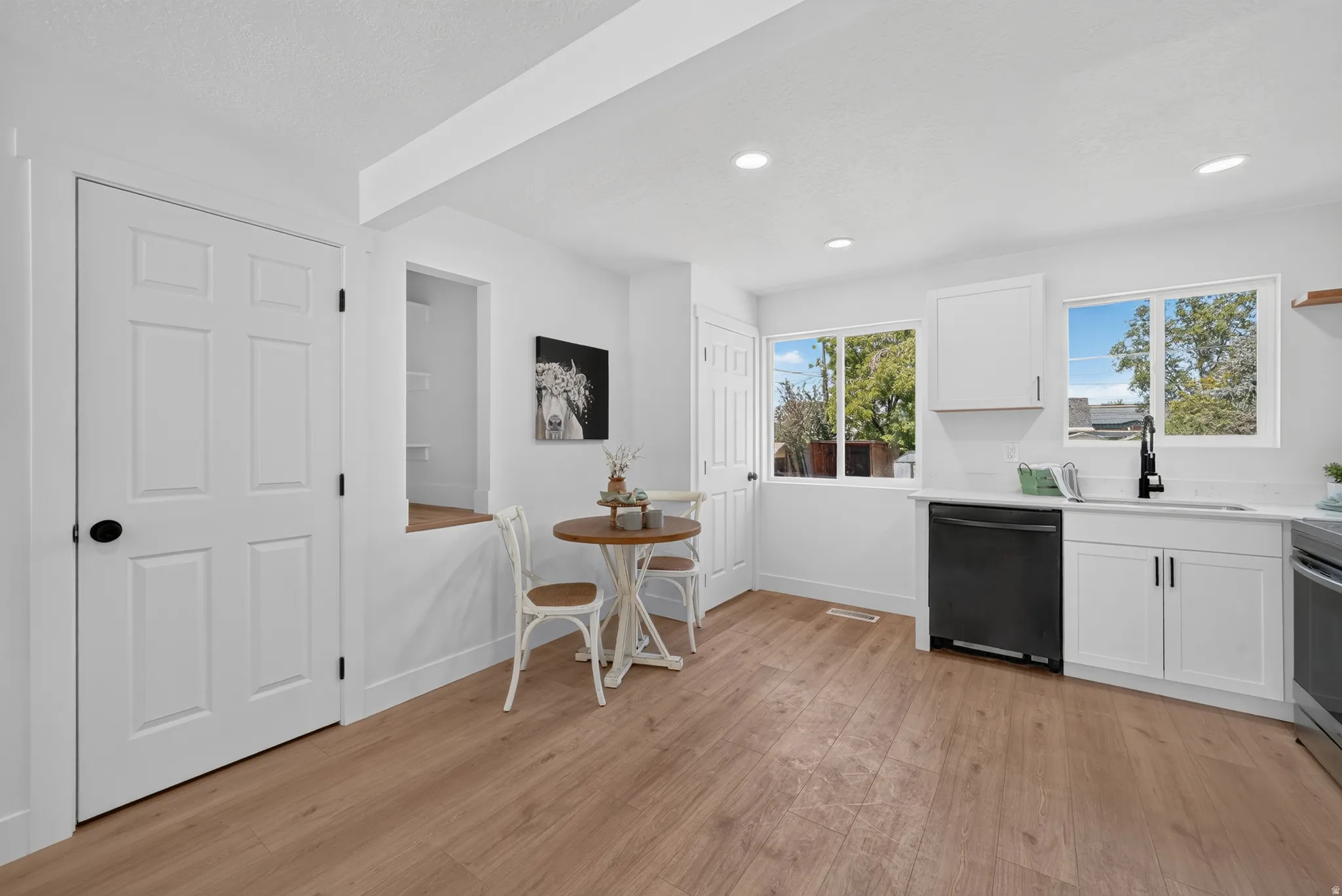 Kitchen featuring white cabinetry, light countertops, wood-finish flooring, two windows, and recessed lighting