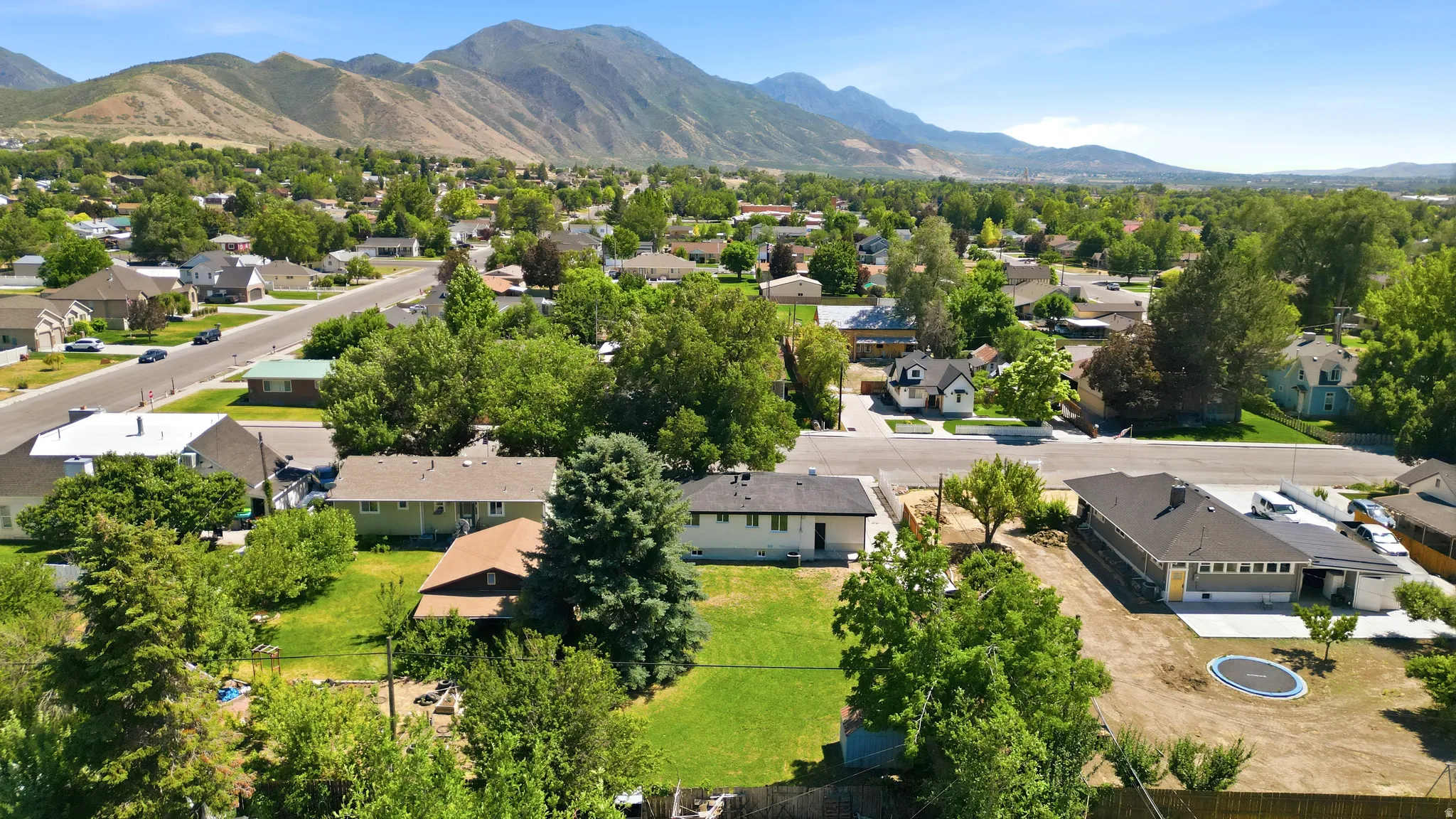 Expansive residential area featuring a variety of single-story and multi-story homes, mature trees, and mountainous terrain in the background