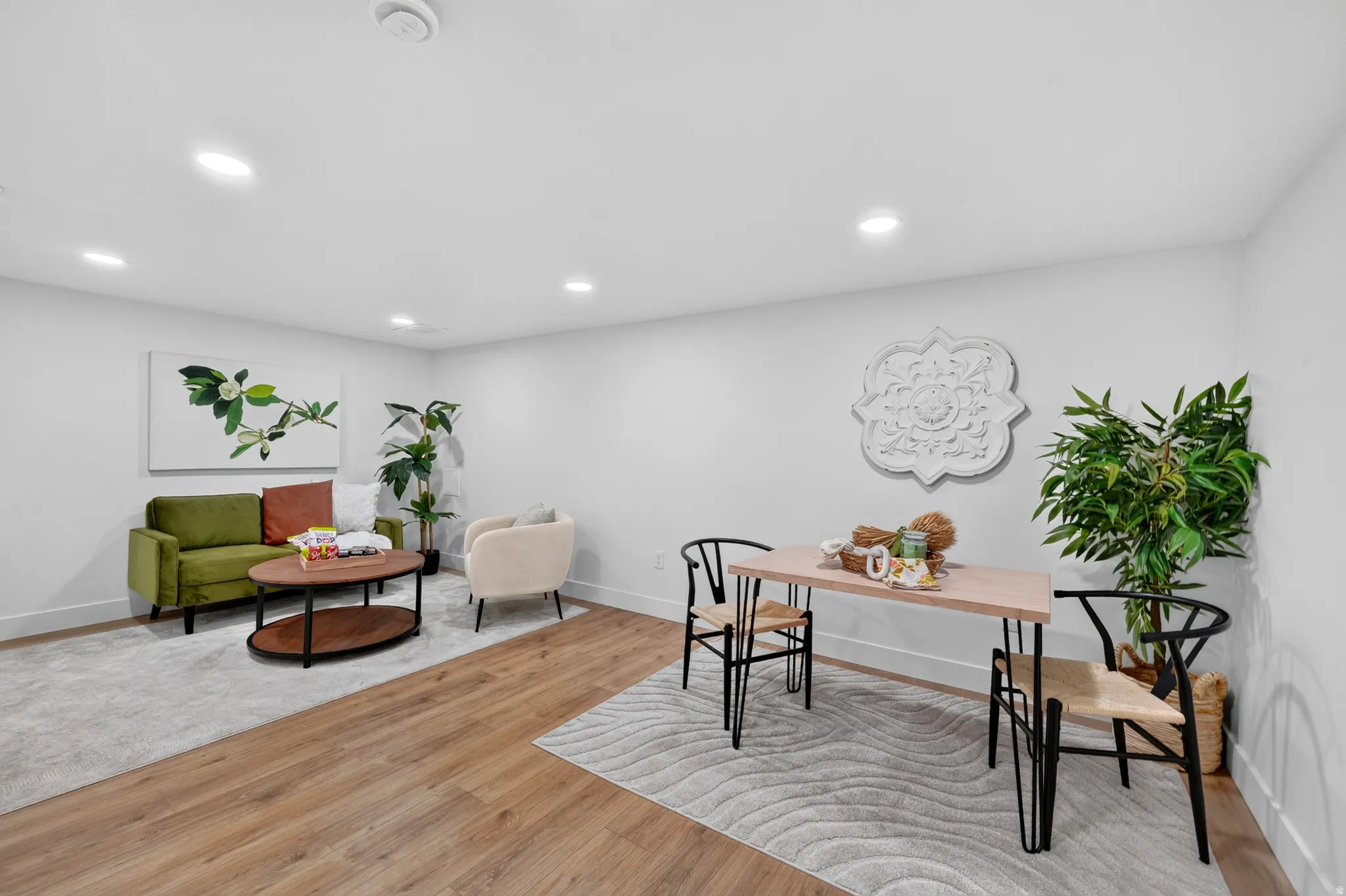 Open-concept living area with wood-finish flooring, recessed lighting, and crisp white walls