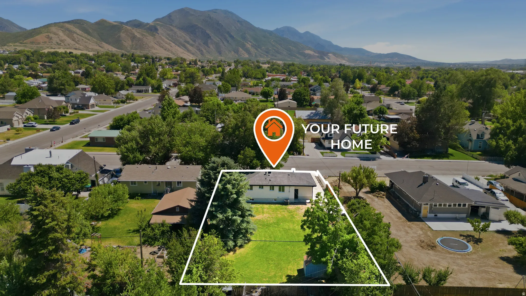 Expansive property featuring a large grassy yard and mature trees, set against a mountain backdrop