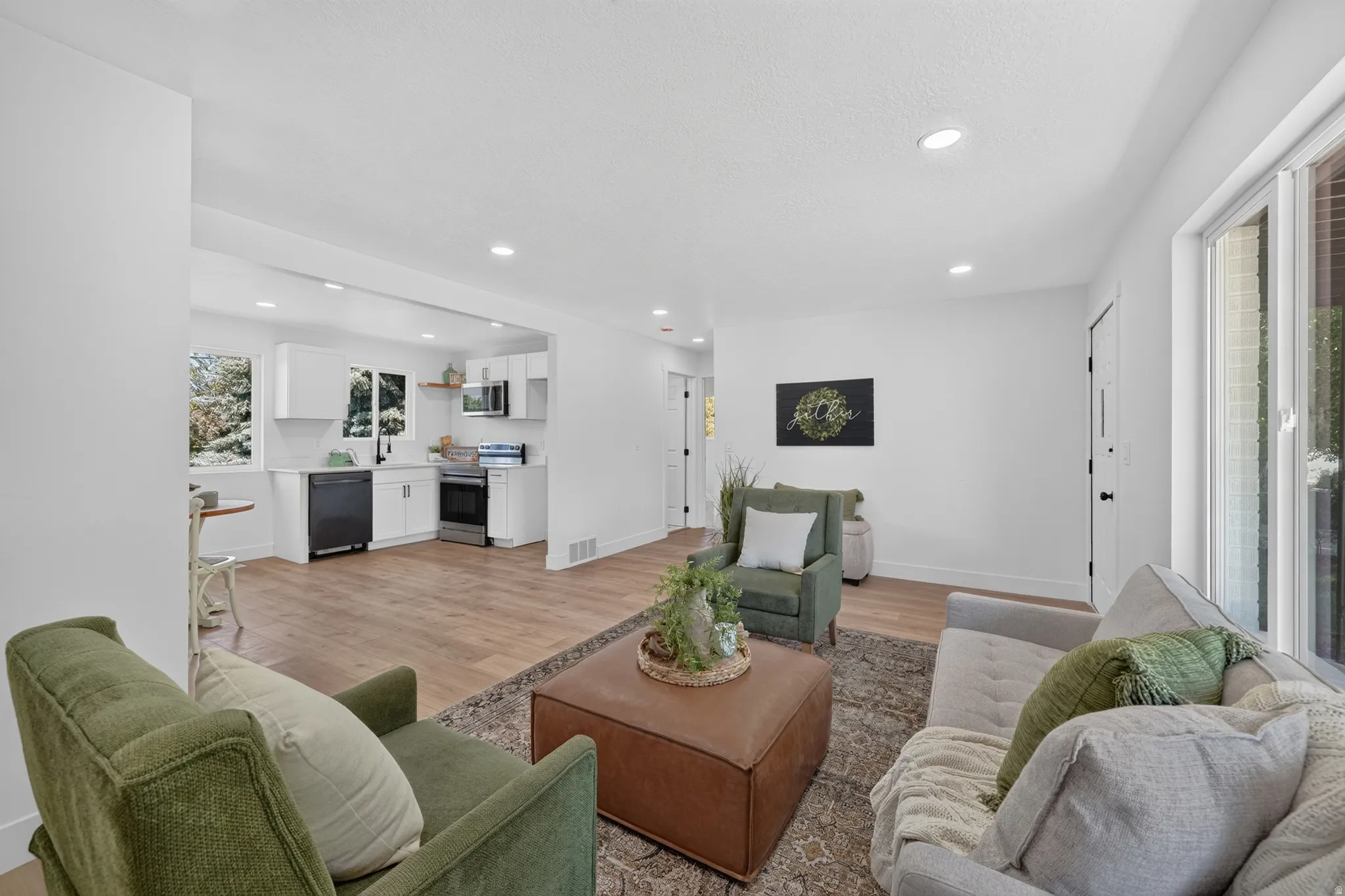 Open-concept living area with wood-finish flooring, recessed lighting, and a neutral color palette