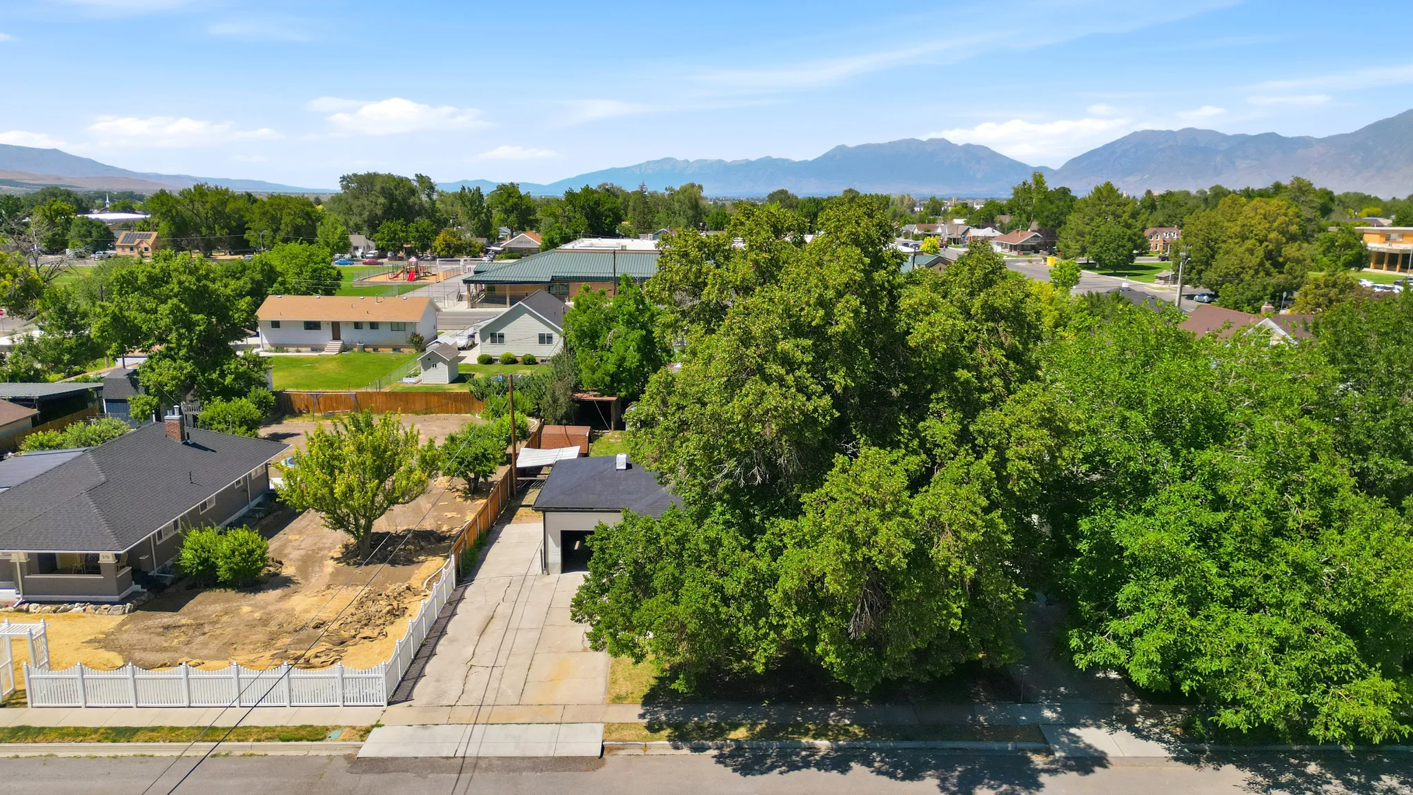 Aerial perspective showcasing the property with a detached garage, a fenced perimeter, and mature landscaping