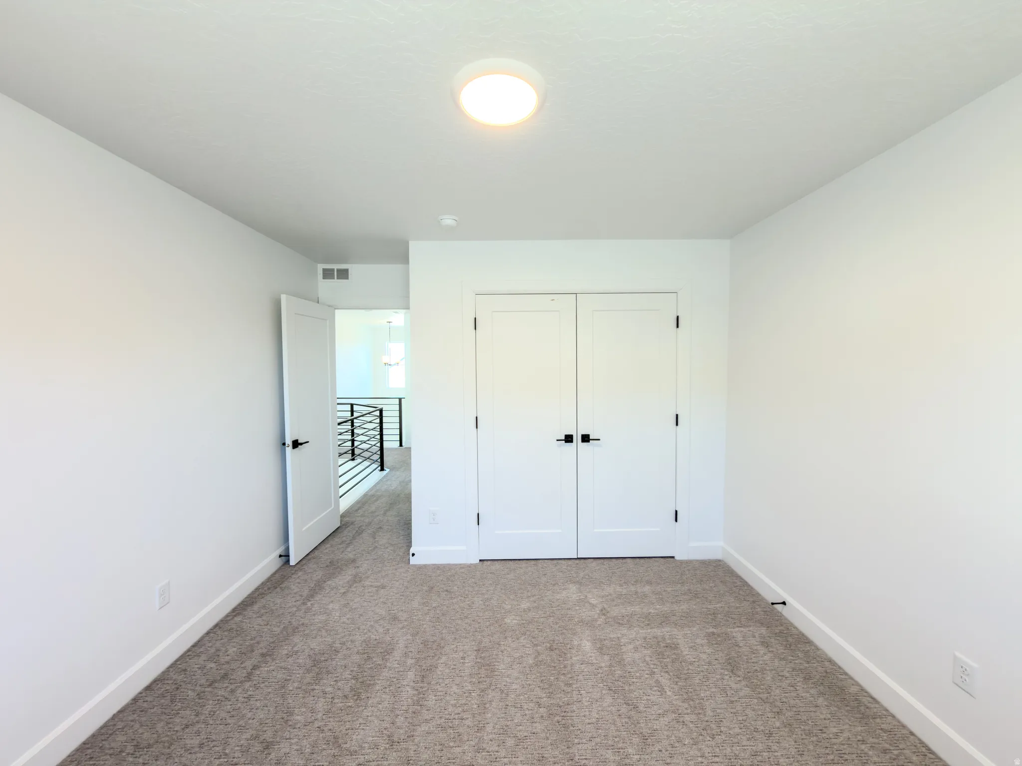 Interior room featuring neutral carpeting, white walls, and a flush-mount ceiling light