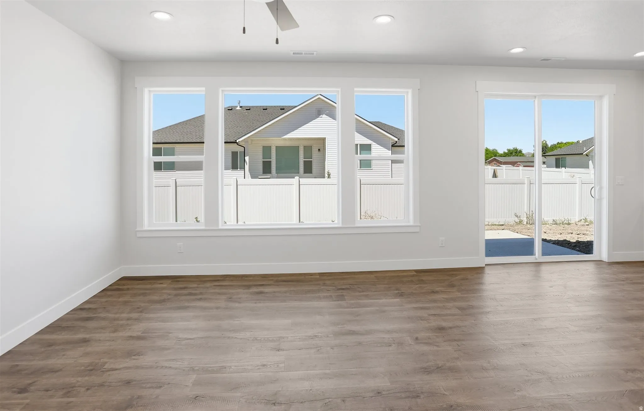 Spacious room featuring wood-finish flooring, recessed lighting, and a ceiling fan