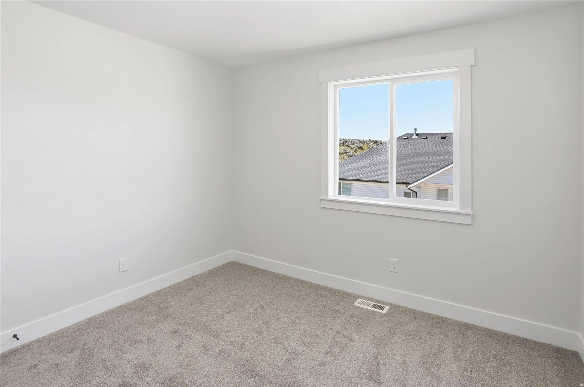 Neutral-toned carpeting paired with white baseboards and window trim
