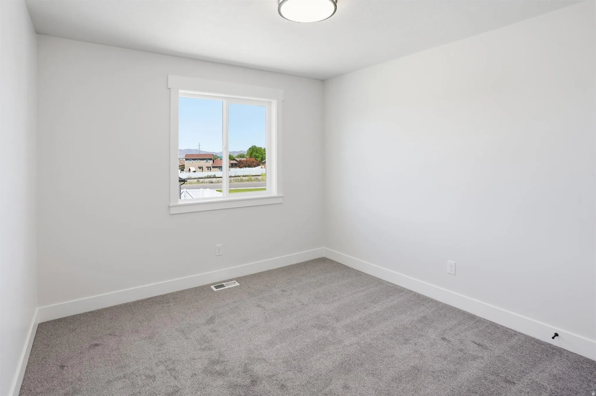 Windowed interior space featuring light gray walls and dark gray carpeting