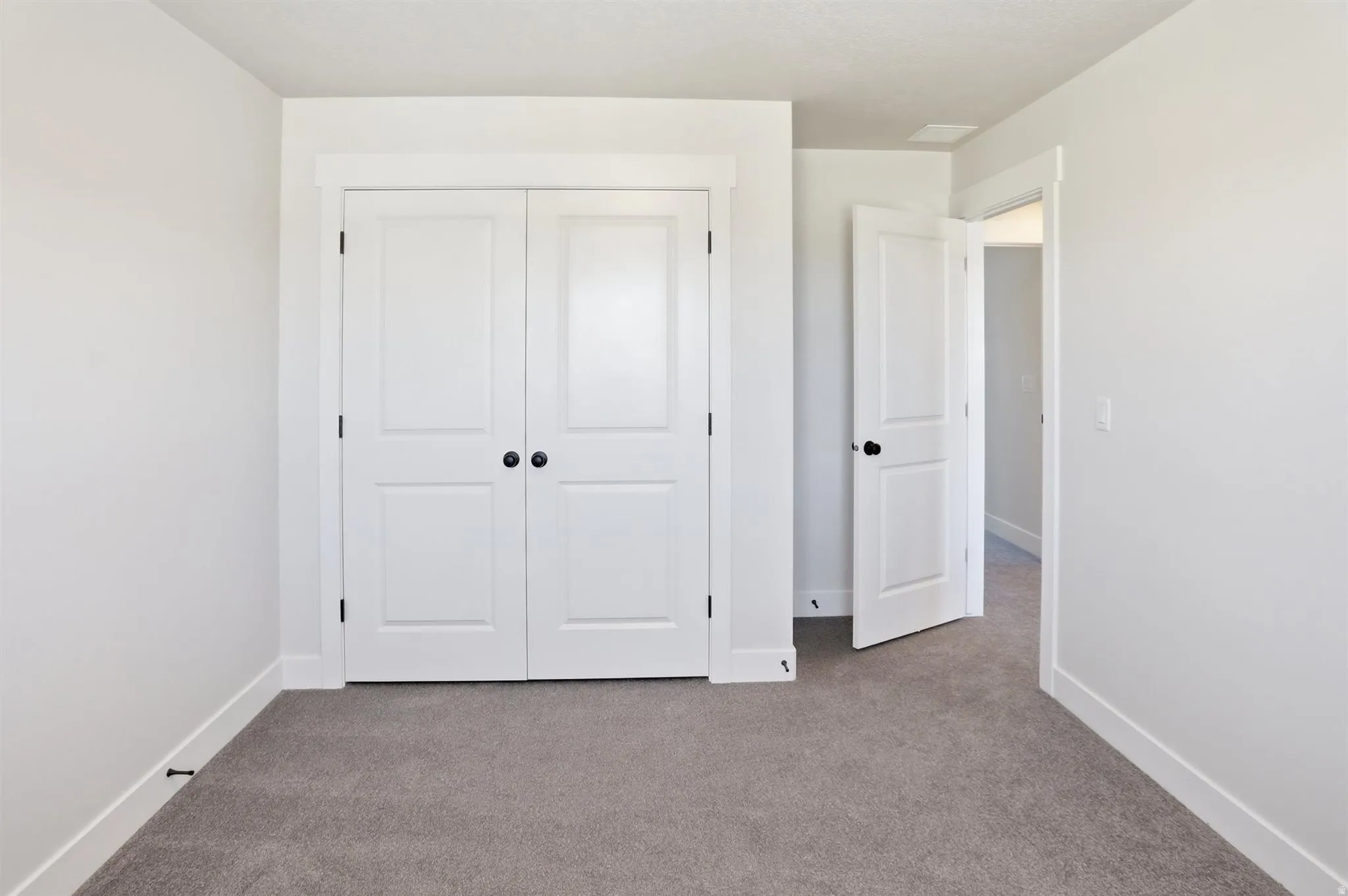 White paneled bi-fold closet doors with matte black hardware