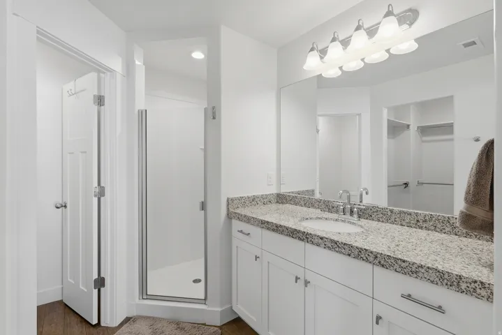 Bright bathroom featuring a spacious vanity with a light granite countertop and white cabinetry