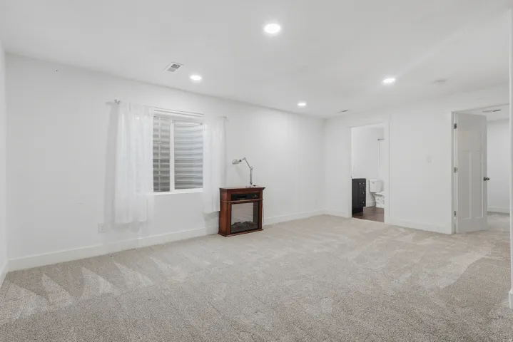Spacious room featuring light-colored carpeting, white walls, and recessed lighting