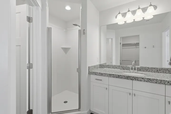 Bathroom vanity featuring a speckled countertop, a single sink with chrome faucet, and white cabinetry