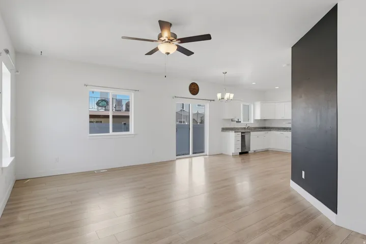 Open-concept living space featuring light wood-finish flooring, white walls, and a contemporary ceiling fan