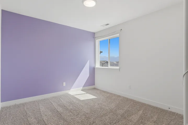 Carpeted room featuring a single window, a purple accent wall, white walls, and a flush mount ceiling light