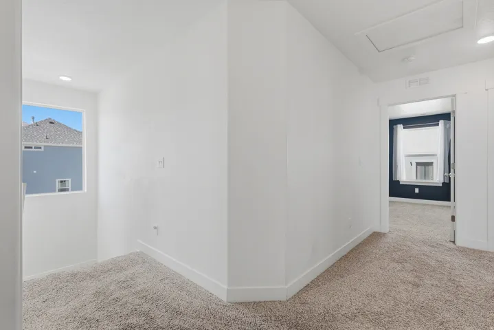 Carpeted hallway with white walls and trim