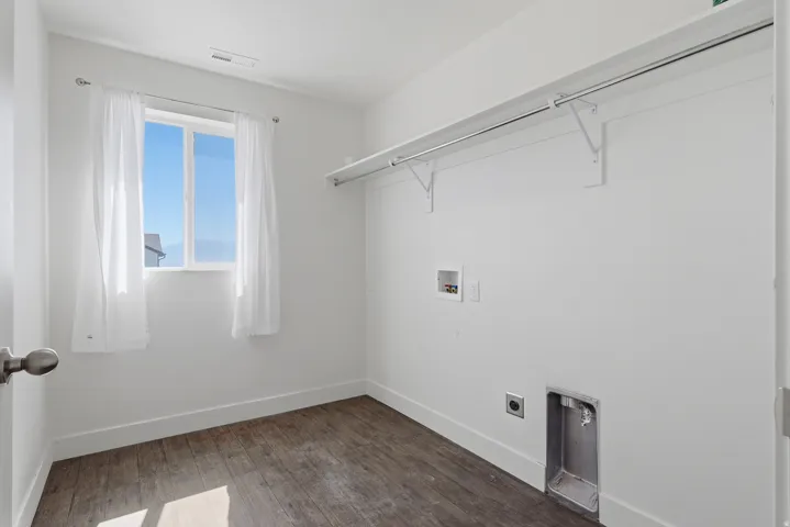Dedicated utility room featuring wood-finish flooring, a bright window, and built-in laundry hookups