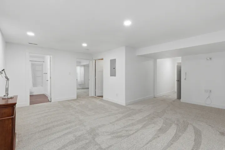 Spacious room featuring light-toned carpeting, recessed lighting, white walls, and white trim