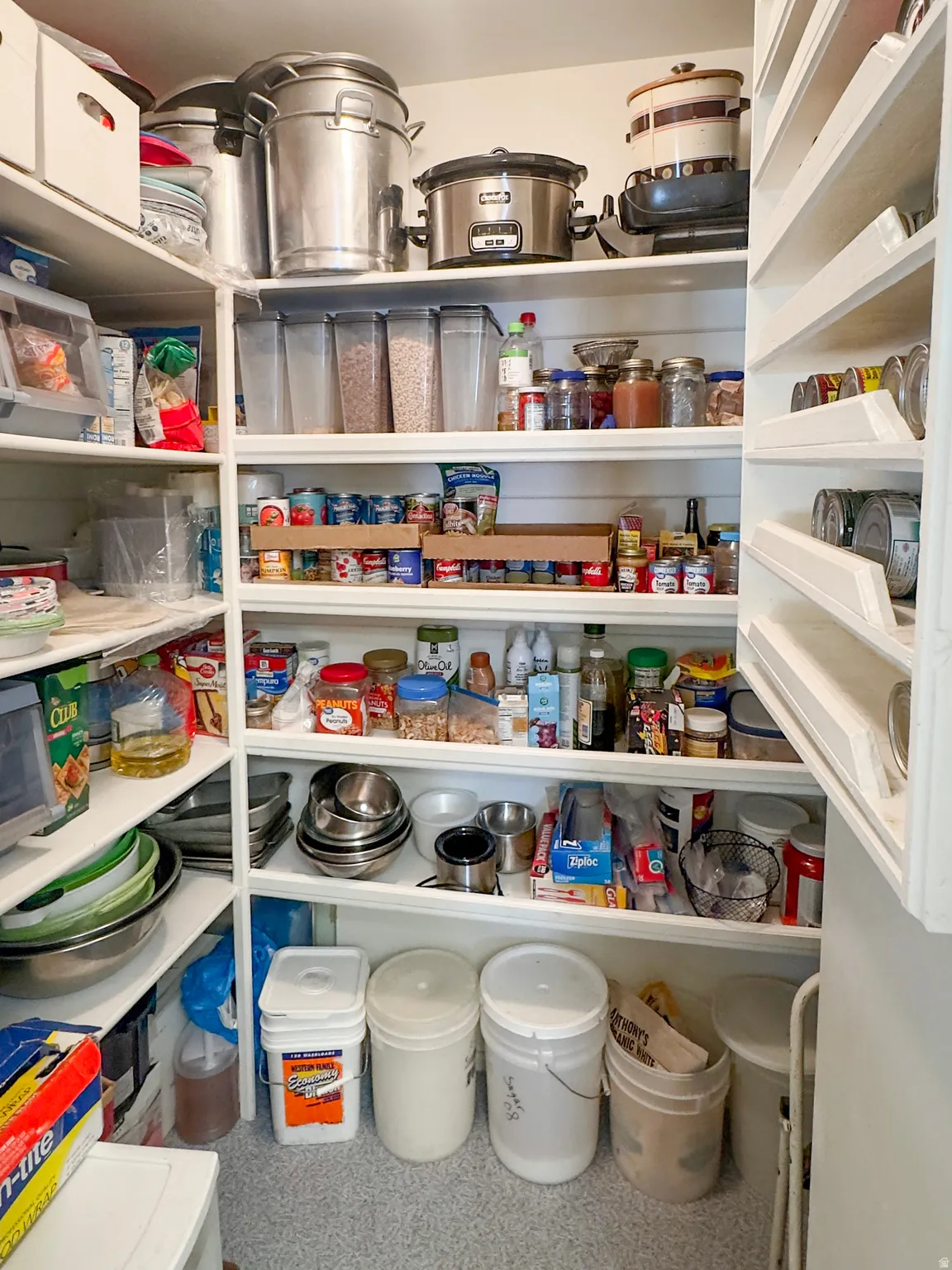 Built-in pantry shelving featuring white wood construction, floor-to-ceiling storage, and integrated can organizers