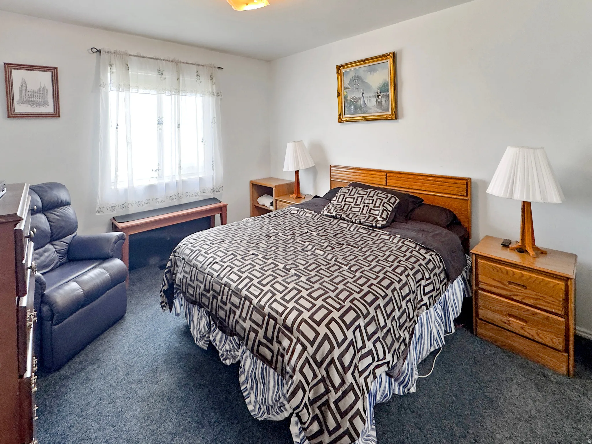 Bedroom featuring a wood headboard, two wood-finish nightstands, and a double window with sheer curtains